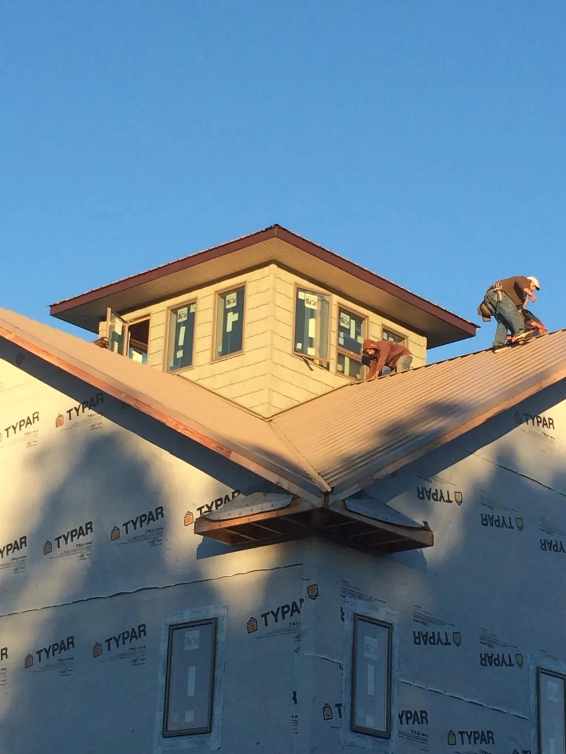 Roofers working around a rooftop cupola on a new metal roof at sunset — Roof Waterproofing in Berlin by Roofing Brothers